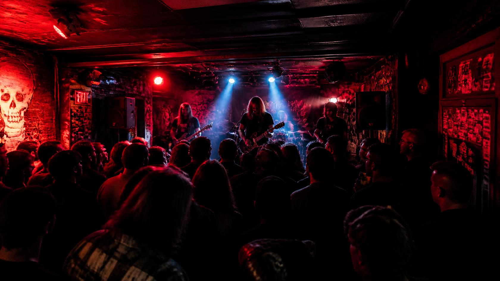 Indie band performing live on an intimate stage under warm spotlights and vibrant venue lighting